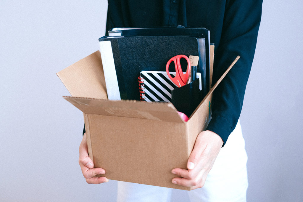 person holding box full of office supplies